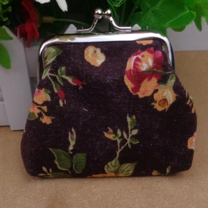 Macro detail of canvas coin purse showing vintage floral pattern and silver kiss-lock buckle
