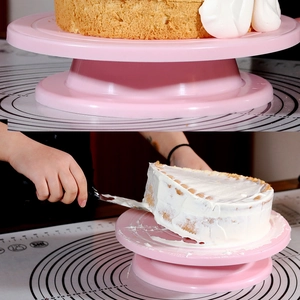 Pink rotating cake turntable being used for frosting a cake with a spatula tool