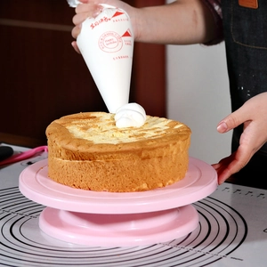 Pink rotating cake turntable and piping bag set showing cream icing application detail
