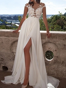 Detailed view of elegant white lace bodice and high-slit chiffon skirt on a long wedding dress