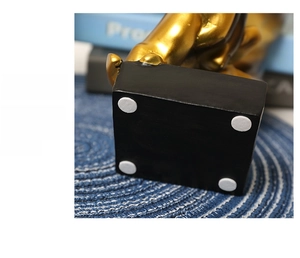 Detail of creative resin statue base with four white anti-slip pads and gold finish