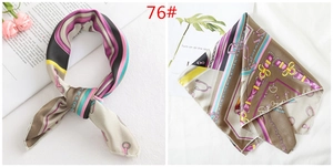 Detailed view of silk-like square scarf featuring classic equestrian harness and buckle motifs