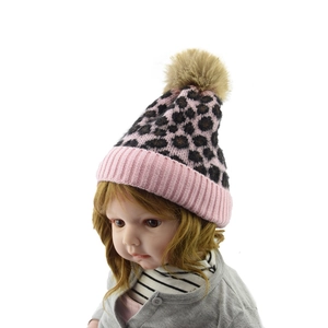 Detail of pink leopard knit beanie with fuzzy pompom and ribbed cuff for winter
