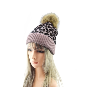 Detailed view of pink leopard knit beanie with fluffy faux fur pom and folded cuff edge