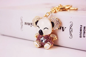 Detailed macro view of a gold koala keychain with white enamel and sparkling pink rhinestones