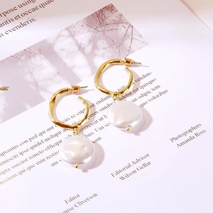 Detail view of long baroque pearl earrings with gold rings on a stylish magazine background