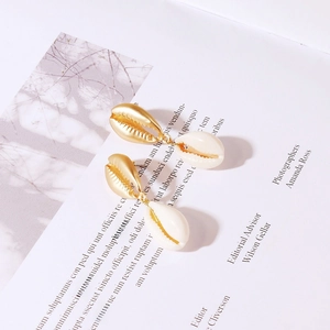 Detail shot of bohemian gold shell earrings featuring a natural white seashell drop
