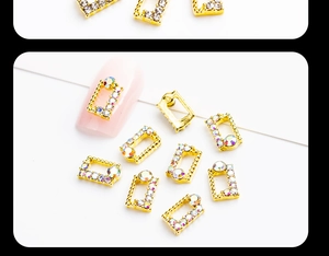 Macro shot of gold rectangle hollow nail charms with aurora rhinestones on pink nails