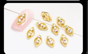 Macro shot of gold diamond-shaped nail charms with iridescent rhinestones for DIY nail art