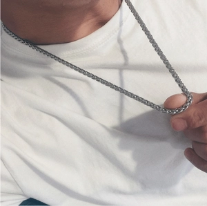 Close-up of silver stainless steel keel chain necklace worn by male model on white shirt