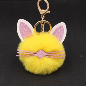 Detail of yellow plush kitten keychain with pink glitter ears and golden hardware accents