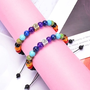 Detail of 8mm lava stone chakra bracelets with Om metal beads on a pink display