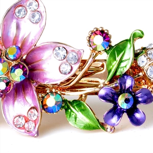 Detailed view of floral enamel hair clip with pink flowers and sparkling rhinestones