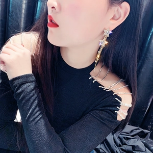 Close-up of star-shaped earrings with crystal inlay and long metal tassel fringe
