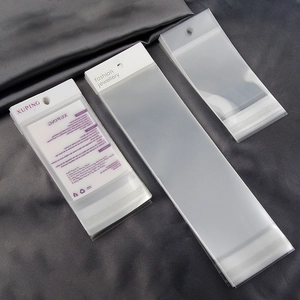 Three sizes of clear jewelry packaging bags with white hanging cards on dark silk background