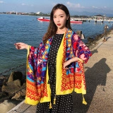Close-up of lightweight ethnic pattern scarf with yellow fringe on a model at the seaside