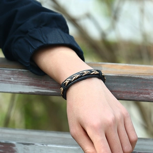 Men's retro braided leather bracelet in black and brown on a wrist in nature