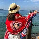 Rear view of a red patterned cotton linen shawl draped over shoulders at the beach