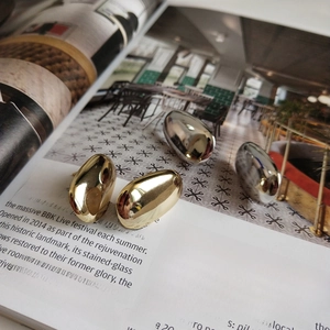 Macro shot of oval gold and silver 925 sterling silver stud earrings on editorial background