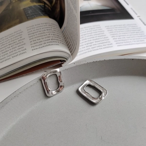 Detail view of irregular rectangular 925 silver earrings with hammered texture on a tray
