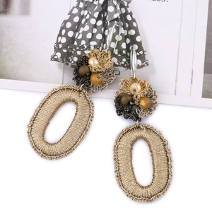 Detailed macro of handmade bohemian earrings with golden woven wire and floral bead accents