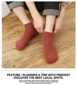 Detailed view of red-brown cotton boat socks worn with denim jeans on wood floor
