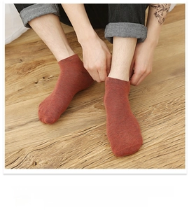Detailed view of red-brown cotton boat socks worn with denim jeans on wood floor