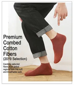 Detail of orange low-cut cotton socks worn with dark cuffed jeans on wooden floor