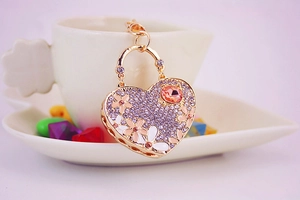 Macro shot of a rhinestone heart keychain with enamel flowers hanging on a cup rim