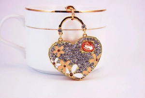 Detail of heart keychain with rhinestones and orange flowers hanging on a white mug