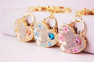 Detailed view of rhinestone heart bag charms with enamel flowers and colorful gemstones