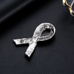 Elegant silver pink ribbon brooch with metal finish on black leather background
