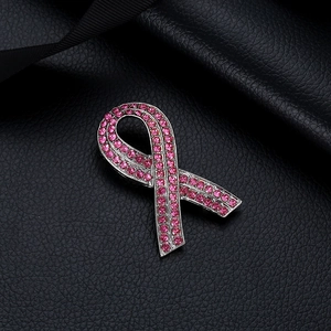 Makroaufnahme einer silbernen Brosche mit rosa Strasssteinen auf schwarzem Leder