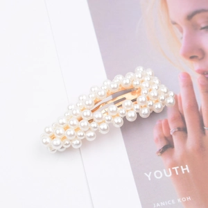 Elegant rectangle hair clip with white pearls and gold metal base on a magazine