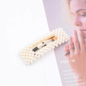 Elegant rectangle hair clip with white pearls on gold metal base set on a magazine