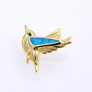 Macro detail of a golden hummingbird pendant with vibrant blue opal inlay craftsmanship