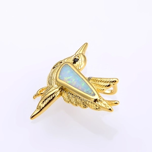 Macro shot of gold hummingbird pendant with iridescent opal inlay and black stone eye
