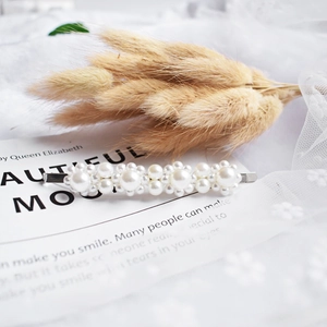 Macro view of elegant pearl hair clip with various sizes of white pearls on silver metal base