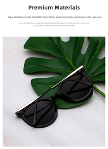Detail of round black sunglasses featuring a gold metal bar on a green monstera leaf