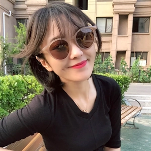 Close-up of beige round retro sunglasses with brown lenses worn outdoors by a model