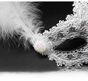 Detail of white feathers and colorful sequin flower on silver lace masquerade mask