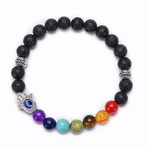 Detail of 7 chakra lava rock bracelet with silver Hamsa Hand and blue Evil Eye charm