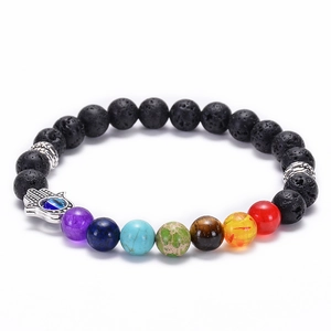 Macro detail of 8mm black lava stone beads with colorful chakra stones and Hamsa hand charm