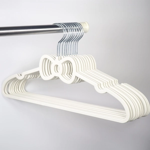 Close-up of cream white bow-shaped non-slip plastic hangers hanging on a metal rod