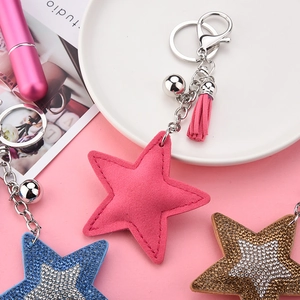 Détail de porte-clés étoiles à paillettes avec pompons et clochettes sur fond rose