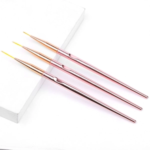 Dettaglio di tre pennelli nail art oro rosa con punte sottili su un supporto bianco