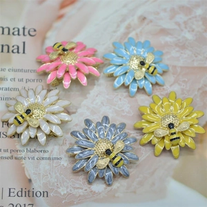 Flat lay of colorful enamel daisy and bee brooches in pink, blue, and white styles