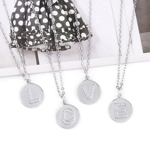 Macro detail of four silver-tone round necklaces with LOVE letter zircon inlay