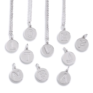 Macro detail of polished silver circular pendants featuring micro-inlaid zircon letters
