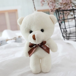 Close-up of small white teddy bear plush keychain with a brown Love ribbon and metal chain